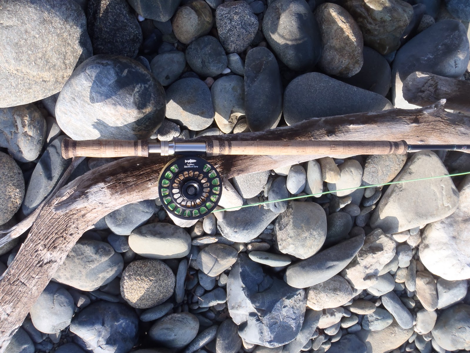 Fly angler casting a spey rod on a misty Pacific Northwest steelhead river with forested banks