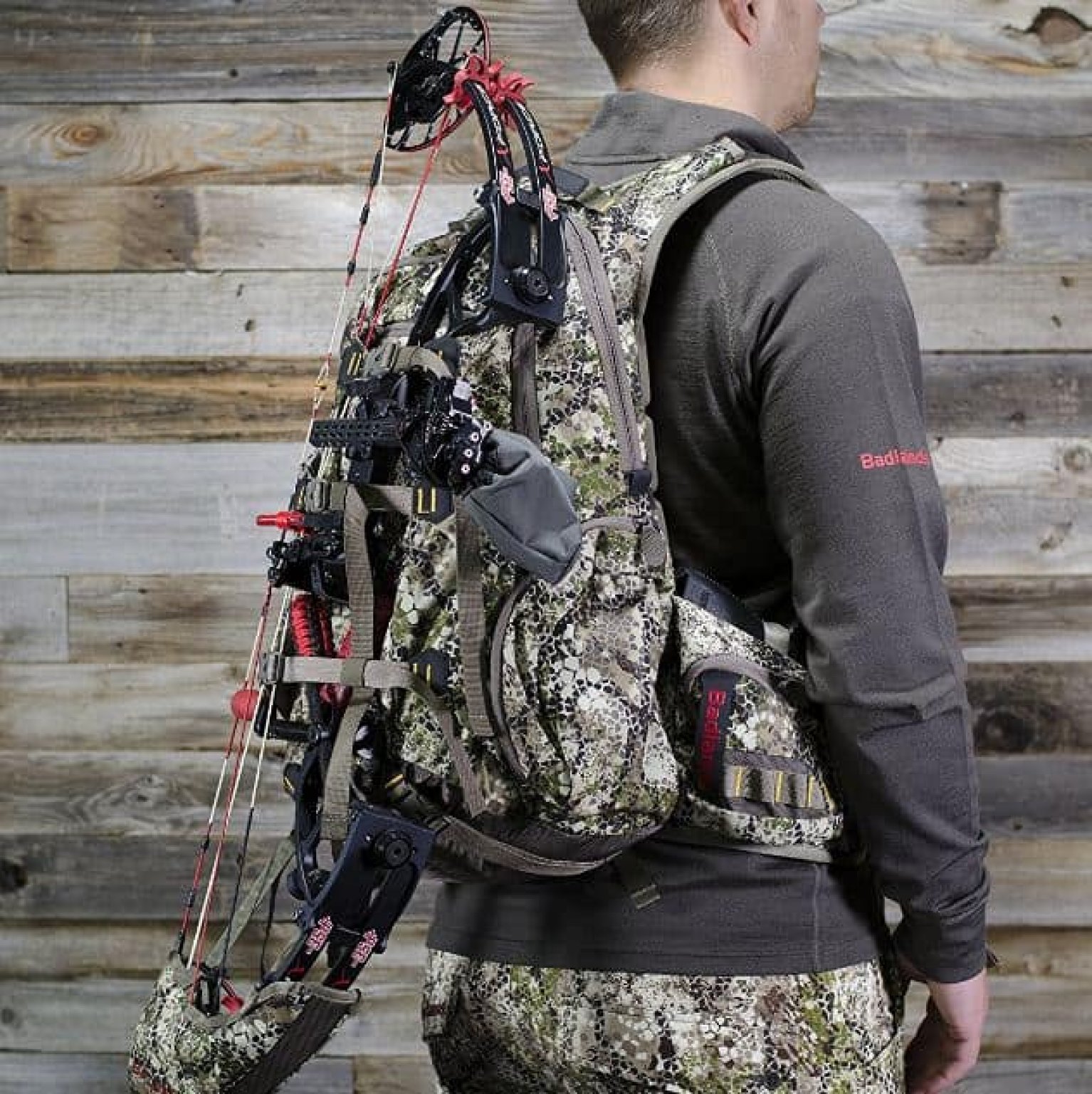 Elk hunting gear laid out including rifle, binoculars, pack, and boots on a tailgate with mountains behind