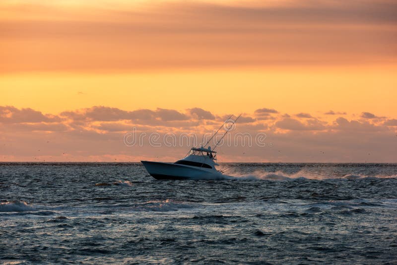 Offshore fishing boat heading out to blue water at sunrise