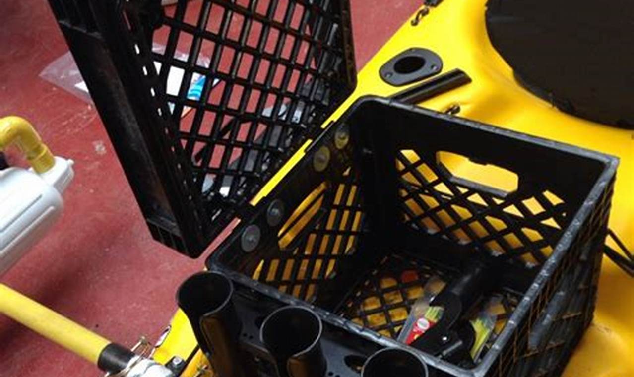 Fully rigged fishing kayak on a lake shore with rod holders, fish finder, and crate system visible